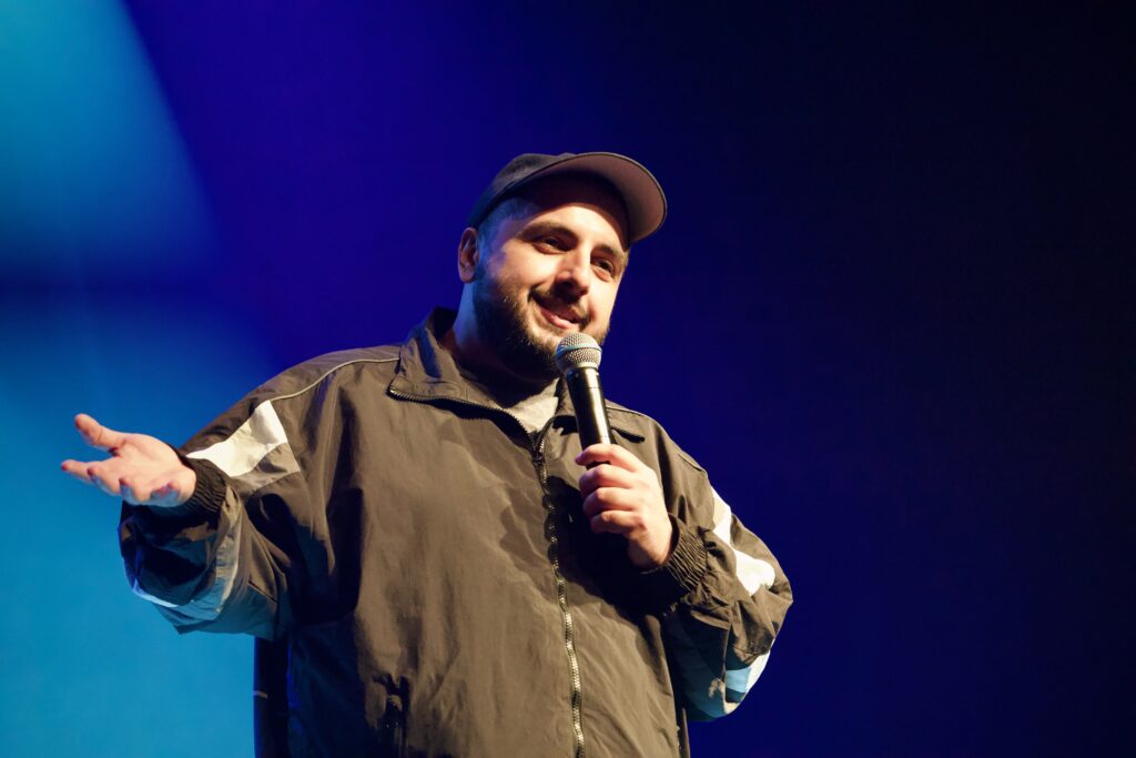 Stand-up Comedian Sezer Oglu mit Mikrofon auf der Bühne im E-Werk Freiburg.